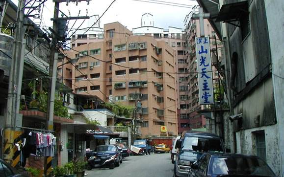 <h2><strong><span style="font-size: 14pt; color: #ff0000;"> ▲山光社區在汐止是一個非常特別的聚落，負載著都市原住民的流浪之歌與流離故事。照片 / 鄭維棕</span></strong></h2><hr /><span style="font-size: 14pt; color: #000000;">照片、文 / 鄭維棕</span><span style="font-size: 14pt; color: #000000;">在汐止，樟樹灣樟樹國小旁的山光社區，是汐止一處非常特別的社區，不僅在汐止山光社區的原民風格非常特殊，即使放諸全台灣，山光社區都是一個特例且風格鮮明的社區。</span><span style="font-size: 14pt; color: #000000;">而這個社區，不僅過往承載著阿美族從花東到台北都會流浪的歷史悲歌，更負載著原住民的文化在都會擁擠且充滿侵略性的風潮下，原住民是否在烽火生活中依然可以延續族民的文化遺緒。</span><span style="font-size: 14pt; color: #000000;">山光社區是1976年間，一群原居於南港大同公寓的阿美族人，看到許多來到都市的原住民，常因為租屋而流離失所、或居住品質不佳，進而起意購屋。這些人組成了十人的購屋委員會，分別至各地尋找適合的地點並召募各地親友購買房子。1979年終於在汐止的山光社區現址找到合適的土地，並於現址建立起阿美族的都市社區。</span><span style="font-size: 14pt; color: #000000;">然而，原本規劃興建300戶住宅，但受制於購買能力有限及當時汐止樟樹灣尚屬偏僻，募集不易，最後只建了166戶，這些承購戶也包括一些漢人。</span><span style="font-size: 14pt; color: #000000;">其後，汐止因為大量人口湧入，樟樹灣也受惠於汐止的發展，原本由八排二層樓式組成的山光社區，也受到建商的青睞，1993年社區內部份居民組成重建委員會，並由五豐建設公司與居民以合建名義，拆除其中二排二層樓式建築，改建成十四樓的鋼筋大樓，並將大樓稱為五豐大樓。</span><span style="font-size: 14pt; color: #000000;">由於山光社區的建立，阿美族居民群聚越來越多，山光社區所在的山光里之外，旁邊的厚德里、忠孝里也聚集了越來越多的阿美族。使得樟樹灣的忠孝、厚德與山光社區成為汐止原住民居住的大本營。</span><span style="font-size: 14pt; color: #000000;">由於原住民的文化所致，目前山光社區內仍維持著頭目制度，在社區內，原住民也一直有自己的組織。也由於人口眾多，過去汐止的代表會中，一直保有一席的原住民代表（如過去代表有林明春）。</span><span style="font-size: 14pt; color: #000000;">另外，這裡的信仰分屬於幾個主要教會，如樟樹長老教會、錫安教會、山光天主堂等。透過這些教會的組織，原住民在這個區域有自己的活動，同時，這些原住民每年也都會舉辦特有的豐年文化季。</span><span style="font-size: 14pt; color: #000000;"><strong>與高鐵爭地血淚史</strong></span><span style="font-size: 14pt; color: #000000;">事實上，除了山光社區的阿美族社群外，汐止另外最有名的就是在東方科學園區後方的「花東新村」。</span><span style="color: #000000;"><span style="font-size: 14pt;">「花東新村」是汐止白匏湖段國有土地內之阿美族原住民聚居住所。這些從花東來台北奮鬥的阿美族，自1980年7月間起迄1996年6月底止，他們北上謀生，因為生存競爭的關係，無力在大台北生存，於是就在汐止東方科學園區後方的光復路的坡地，相繼搭建木板房屋，當時的住戶約205戶，共600餘人，佔地面積約達1.3公頃，可以說是山光原住民社區外，汐止最大的原住民部落。</span><span style="font-size: 14pt;"><img class="size-full wp-image-2132 aligncenter" src="https://iformosa.org/wp-content/uploads/2016/04/樟樹長老教會.jpg" alt="樟樹長老教會" width="579" height="362" /></span></span><strong><span style="font-size: 14pt; color: #ff0000;">▲樟樹長老教會是山光社區居民的主要信仰之一。</span></strong><hr /><span style="font-size: 14pt; color: #000000;">然而，1990年間，政府把光復路這一段劃歸為高鐵調車場計畫用地。規劃後這塊土地成為高鐵與阿美族部落的爭奪地。1998年時，當時的總統李登輝曾於2月3日巡視「花東新村」，並指示行政部門應以專案小組協助「拆遷安置」方式，儘速解決。</span><span style="font-size: 14pt; color: #000000;">事實上，花東新村由於沿著河邊與山坡搭建，都是木頭做的違建，沒水沒電，因此，曾於1997年秋天發生大火，燒毀了16戶住宅。當時，自治會的頭目黃先生也曾組織族民，希望政府多多關心原住民的處境，在當時媒體也曾大肆報導過。</span><span style="font-size: 14pt; color: #000000;"><img src="http://www.sinew.idv.tw/images/p%E6%9D%B1%E6%96%B9%E7%A7%91%E5%AD%B8%E5%9C%92%E5%8D%80.jpg" alt="" /><img class="size-full wp-image-2133 aligncenter" src="https://iformosa.org/wp-content/uploads/2016/04/東方科學園區.jpg" alt="東方科學園區" width="579" height="362" /></span><span style="font-size: 14pt; color: #000000;">▲東方科學園區後方的「花東新村」，曾是阿美族人在大都會荊棘生活中的避難所。華麗的大樓背後，卻是各種流離的悲歌。照片 / 鄭維棕</span><hr /><span style="font-size: 14pt; color: #000000;">1998年，行政院原民會曾專案處理花東新村臨時安置的事宜。從調查、開會、找地、公告、招標、發包、驗收與安置，歷時約兩年，並由當時還未改制的臺北縣政府接管。原舊花東新村225戶，抽籤安置123戶。其中以阿美族人佔絕大部分。</span><span style="font-size: 14pt; color: #000000;">然而，即使如此，在都會生存的原住民卻是荊棘重重，原被劃歸為高鐵機場用地的原花東新村，經過十多年的巨變，依舊閒置在該處。高鐵機場用地已經轉移到南港，三鐵共構的南港交通優勢，不論從人口、位置和交通環境，高鐵根本無須還要轉到這個幾公里外的荒煙谷地重新花大錢建設，但卻沒有實質效益。散落的阿美族部落還一直希望有機會重返這塊原先落腳的沒水沒電土地。然而，這麼多年過去了，這樣的願望，似乎依舊咫尺天涯！</span><span style="font-size: 14pt; color: #000000;"><iframe src="https://www.youtube-nocookie.com/embed/ONWPu8iRawY?rel=0" width="640" height="480" frameborder="0"></iframe></span><span style="font-size: 14pt; color: #000000;">▲原民台曾經報導花東新村。</span>